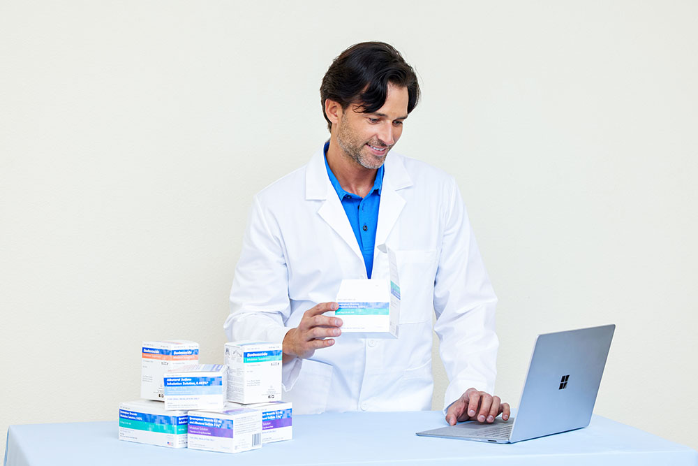 Pharmacy White Male Pharmacist Smiling Laptop Holding Unit Dose Medications Albuterol SulfateIpratropium Bromide